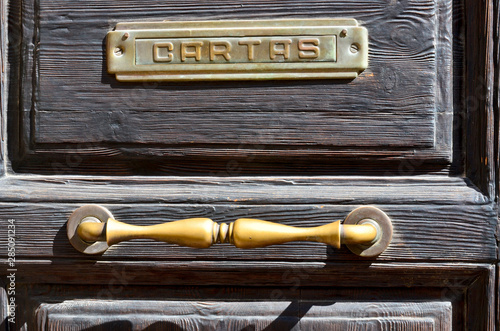 Wooden door with iron fittings and shadows (traslation: letter) photo