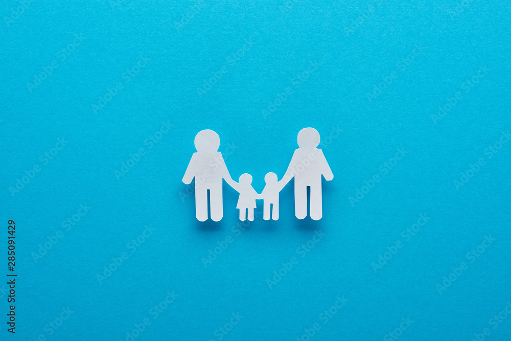 top view of paper cut family holding hands on blue background top view of paper cut family holding hands on blue background