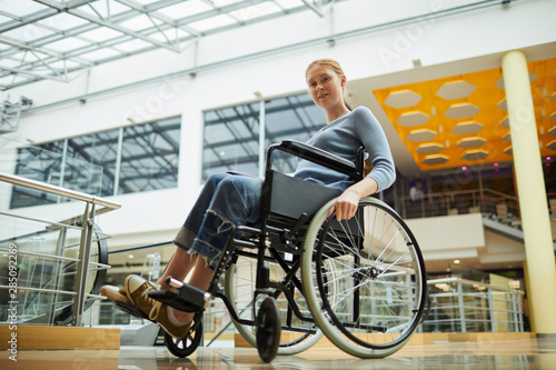 Portrait of young red-haired woman sitting in wheelchair and looking at camera she is going for shopping