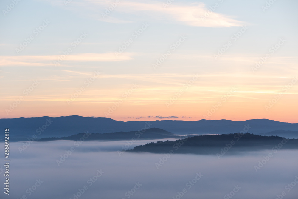 view of sunrise over the mountains mist and clouds under peaks