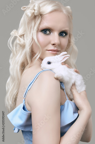 Albino blond girl in elegant dress posing with cute little rabbit