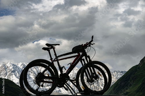 silhouettes of two bicycles on a background of snowy mountains in the Caucasus