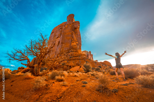 Billede på lærred Beautiful figures of giant stones inside the Monument Valley National Park and a lifestyle girl with black shirt and raised arms