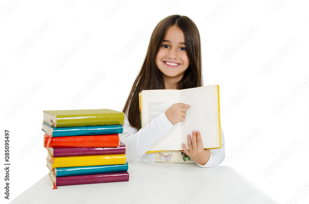 Back to school and happy time! Cute industrious child is sitting at a desk pointing on blank page of book. Isolated on white background. Girl reading the book Back to school and happy time! Cute industrious child is sitting at a desk pointing on blank page of book. Isolated on white background. Girl reading the book