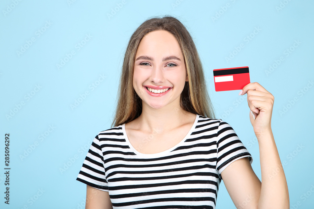 Beautiful young woman holding credit card on blue background Beautiful young woman holding credit card on blue background