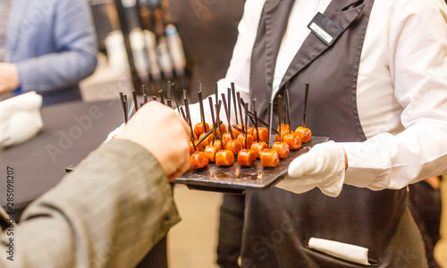 Bilde på lerret Waiter wearing white gloves and black apron holds a tray with cold snacks