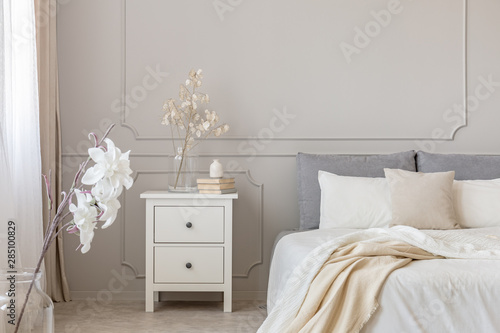 Papier peint Flowers on nightstand table in delightful bedroom interior with grey and white d