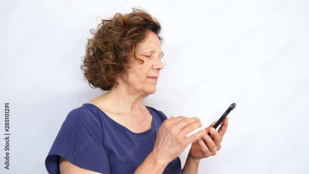 Mature woman reacting to loss and using smartphone isolated on white background. Shot in 4K Mature woman reacting to loss and using smartphone isolated on white background. Shot in 4K