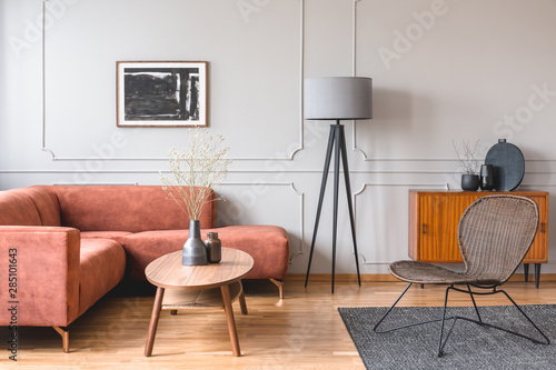 Stylish tall grey lamp in elegant living room interior with comfortable brown corner sofa © Photographee.eu