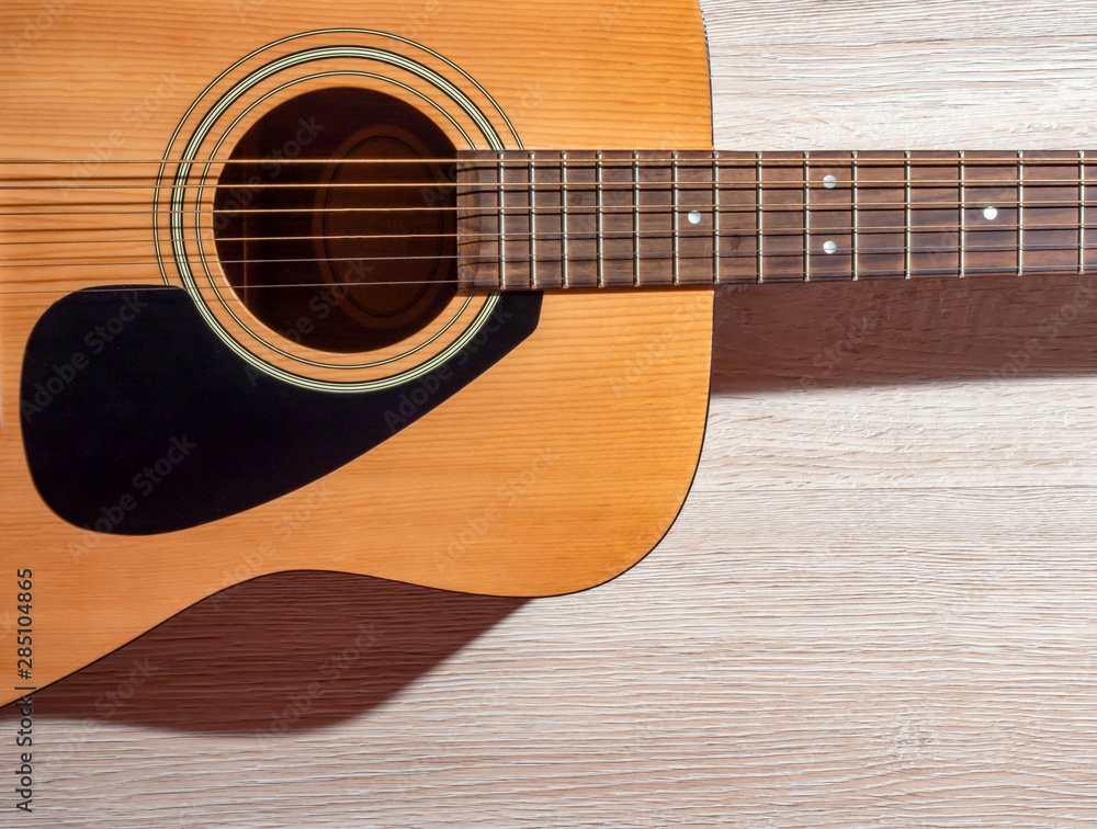 Obraz premium Classical acoustic guitar brown on light wooden background