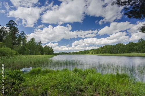 Gorgeous view of forest lake landscape on blue sky and white clouds background. Sweden. Europe.