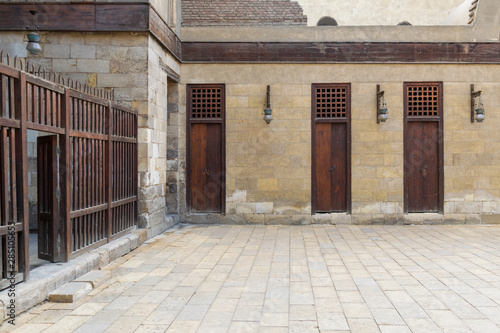 Three adjacent doors in a stone bricks wall and wooden fence at the main courtyard of public historic mosque of Sultan Al Nassir Qalawun, Cairo, Egypt © Khaled El-Adawi