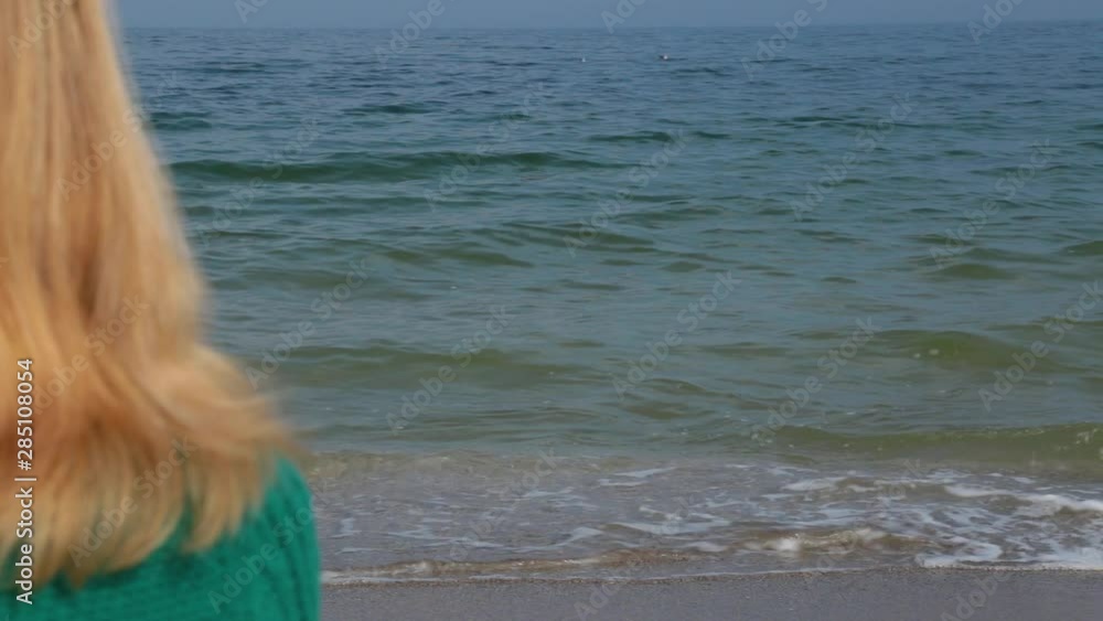 Closeup back view of blond beautiful woman sitting alone at beach ...