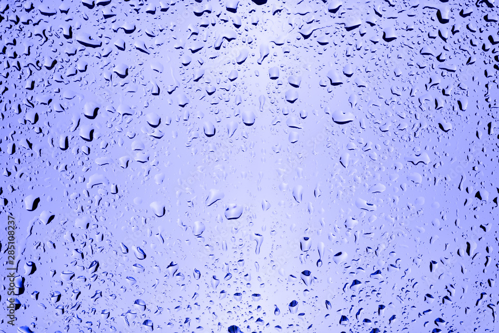Drops of water flow down a transparent glass on a purple background. Drops of water flow down a transparent glass on a purple background.