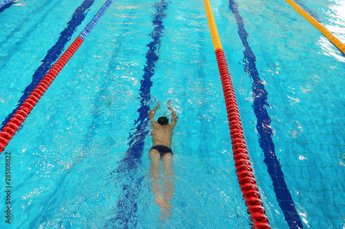 Athlete trains in the pool with clean water. Top view