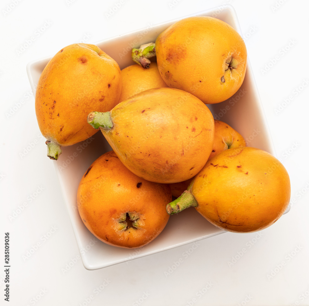 Fresh loquats (medlars) in bowl. Isolated on white background. Close-up.Top view. Fresh loquats (medlars) in bowl. Isolated on white background. Close-up.Top view.
