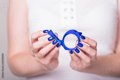 Beautiful female hands holding decorative blue bird. Manicure with blue nail polish. Toned