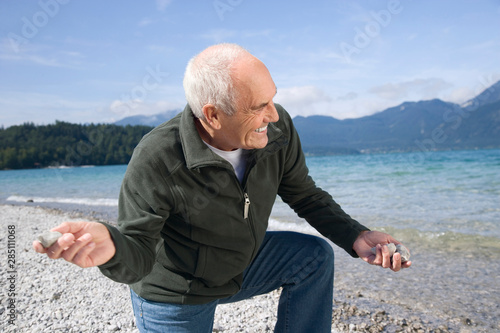 Germany, Bavaria, Walchensee, Senior man on lakeshore, skimming a stone