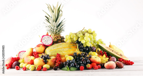 Tropical fruits background, many colorful ripe fruits with strawberries, grapes and cherries on wooden background