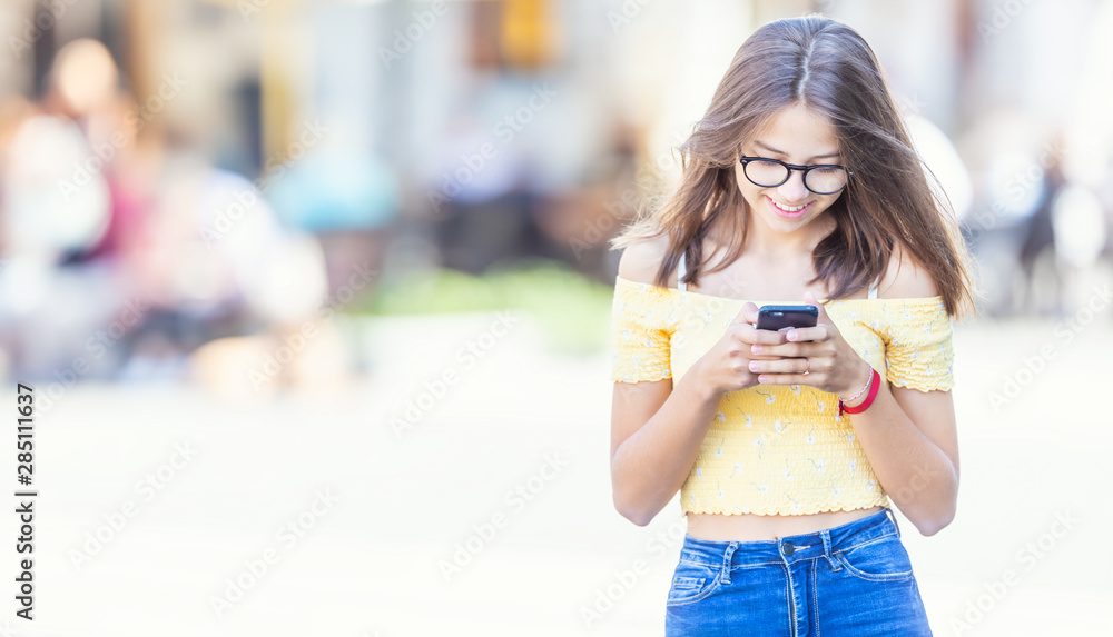 Young student girl texting on her smartphone and smiling