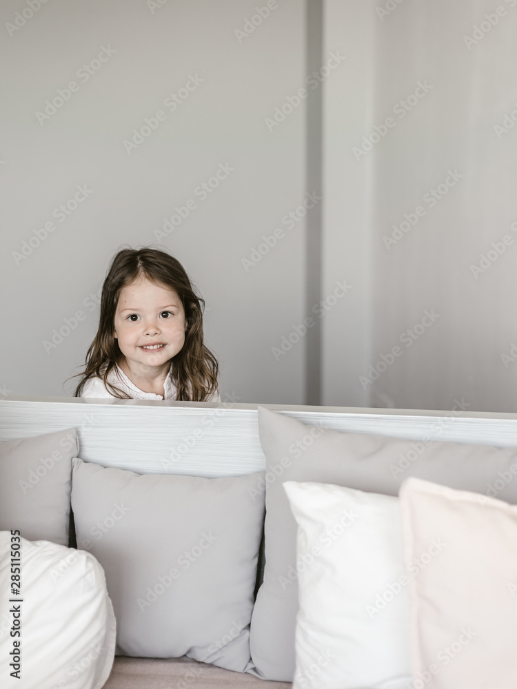 Little girl peeking out bed headboard Little girl peeking out bed headboard