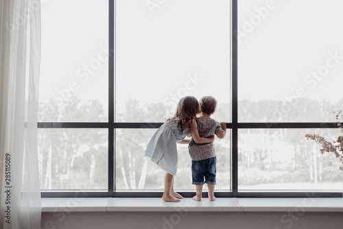 Children on sill looking out window photo