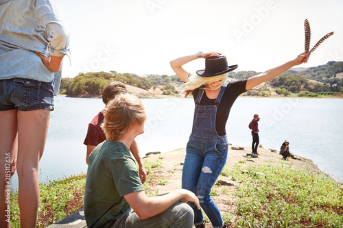 Woman dancing with friends in nature by a lake photo