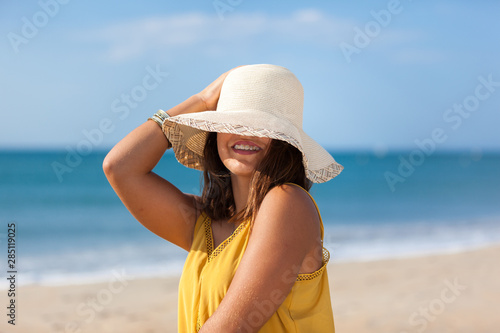 Portrait fashion of pretty young woman with straw hat on a beach in Summer. Happy Smiling girl..
