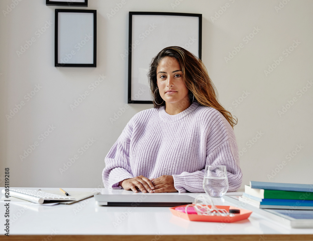 Young professional woman working on a laptop at a desk in her bright and modern home office. Young professional woman working on a laptop at a desk in her bright and modern home office.