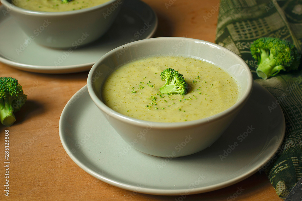 Fresh Broccoli cream soup on two gray ceramic bowl on plate with spoon on marble background,vegetarian food,healthy concept Fresh Broccoli cream soup on two gray ceramic bowl on plate with spoon on marble background,vegetarian food,healthy concept