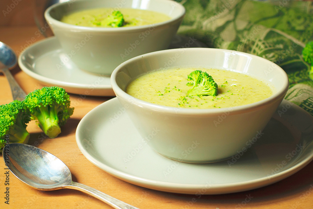 Fresh Broccoli cream soup on two gray ceramic bowl on plate with spoon on marble background,vegetarian food,healthy concept Fresh Broccoli cream soup on two gray ceramic bowl on plate with spoon on marble background,vegetarian food,healthy concept