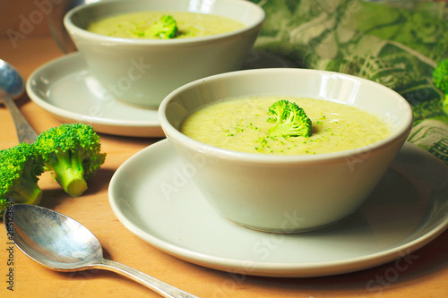 Fresh Broccoli cream soup on two gray ceramic bowl on plate with spoon on marble background,vegetarian food,healthy concept