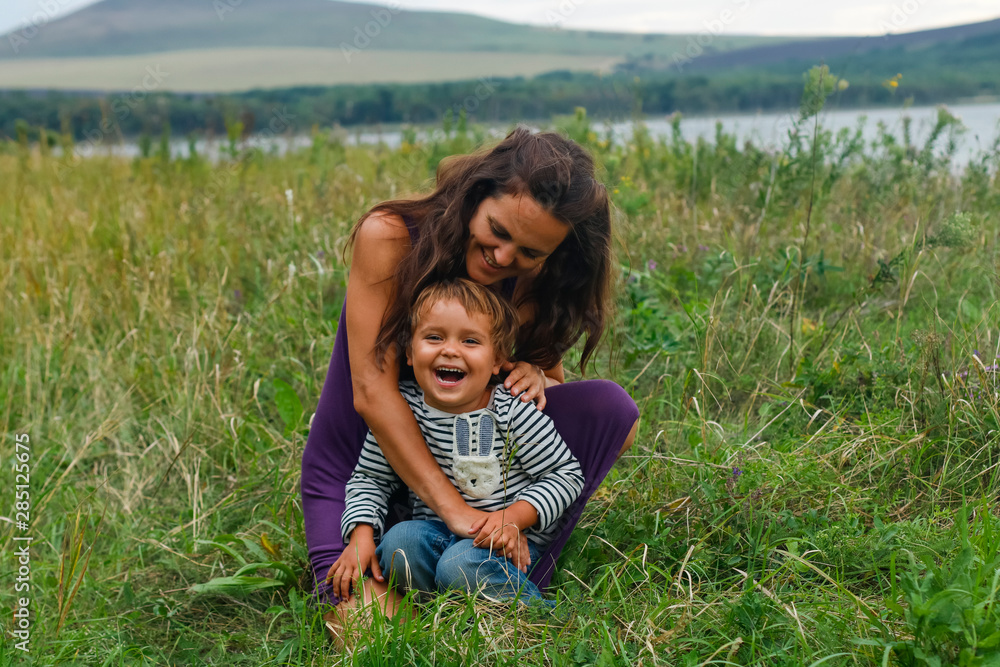 Fototapeta premium Happy family having fun on vacation. happy and harmonious family in the fresh air. mother and son laughing and playing in the summer on the nature. Happiness and joy, fun.