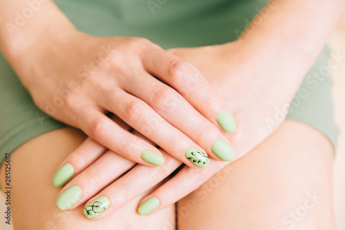 Female hands with trendy manicure of green color.