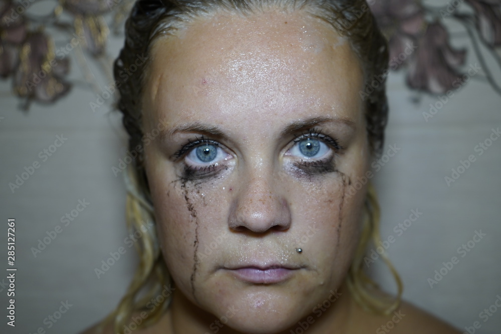 Flowed mascara on the blue eyes of the girl. Wet girl with leaking