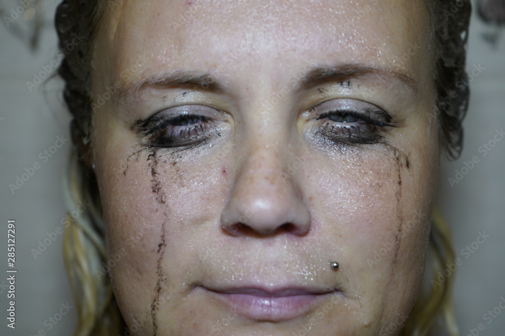 Flowed mascara on the blue eyes of the girl. Wet girl with leaking mascara in front of her eyes. Face close up. Flowed mascara on the blue eyes of the girl. Wet girl with leaking mascara in front of her eyes. Face close up.