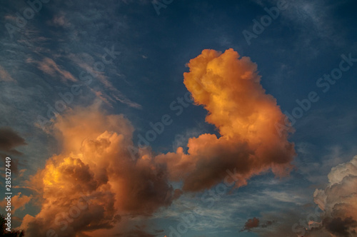 Large fiery orange thick clouds at sunset in sky with wispy clouds, HDR.
