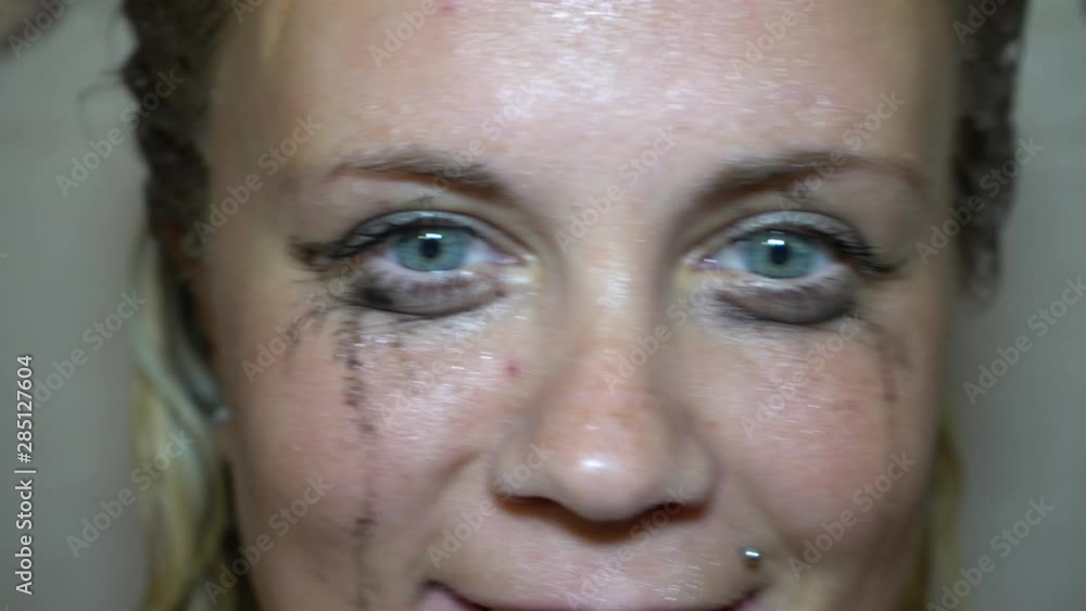 Flowed mascara on the blue eyes of the girl. Wet girl with leaking mascara in front of her eyes. Face close up. Flowed mascara on the blue eyes of the girl. Wet girl with leaking mascara in front of her eyes. Face close up.