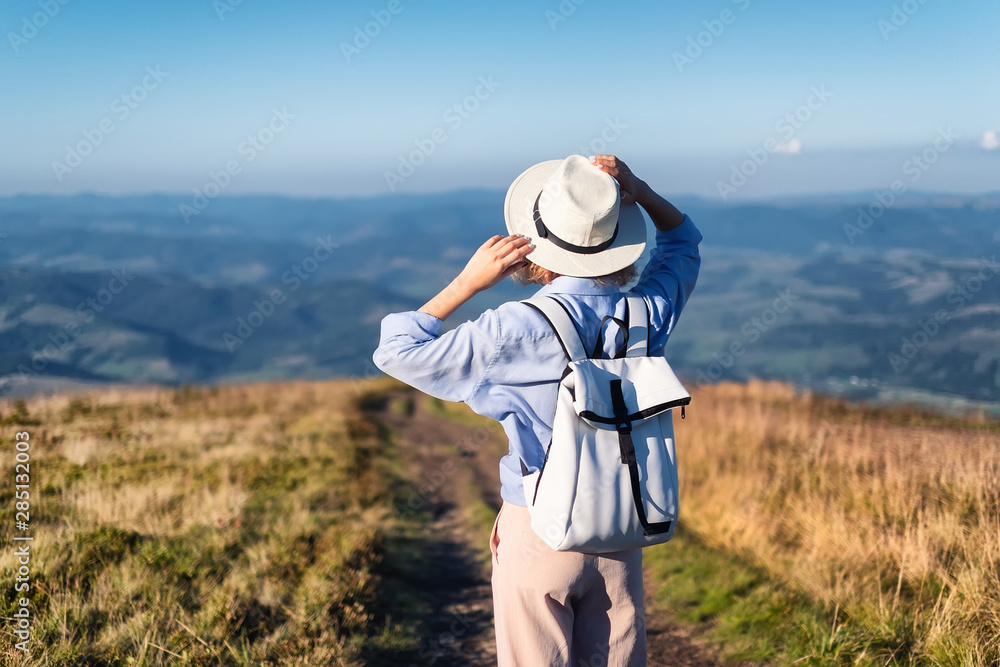 Hiker with a backpack in the mountains. Young girl walking in the mountains during sunset. Mountains and people. Adventure and travel - image Hiker with a backpack in the mountains. Young girl walking in the mountains during sunset. Mountains and people. Adventure and travel - image