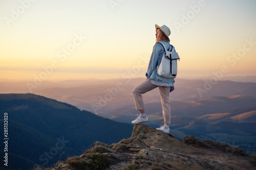 Hiker with backpack in the top of the mountain. Young girl walking in the mountains during sunset. Mountains and people. Adventure and travel - image