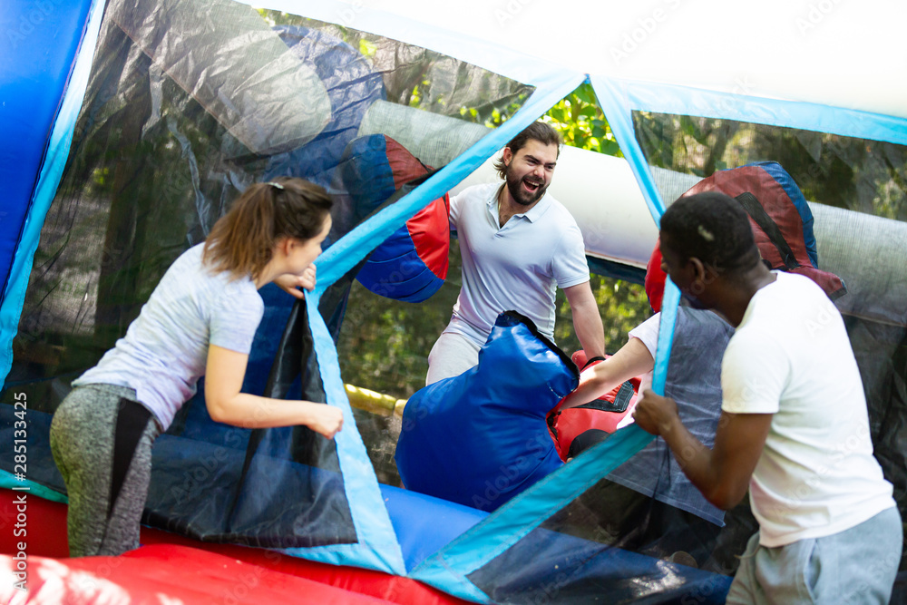 Gambling friends boxing giant gloves on an inflatable trampoline in an amusement park