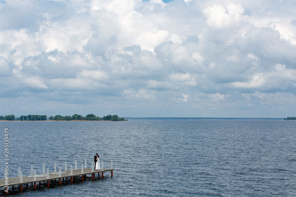 bride and groom walking on the bridge near the river.wedding day. bridal walk outdoors.portrait of newlyweds in nature