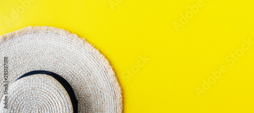 Eco friendly wicker Straw hat over yellow background with space for text, top view, wide composition. Summer vacation fashion, holiday concept. Beach accessories.