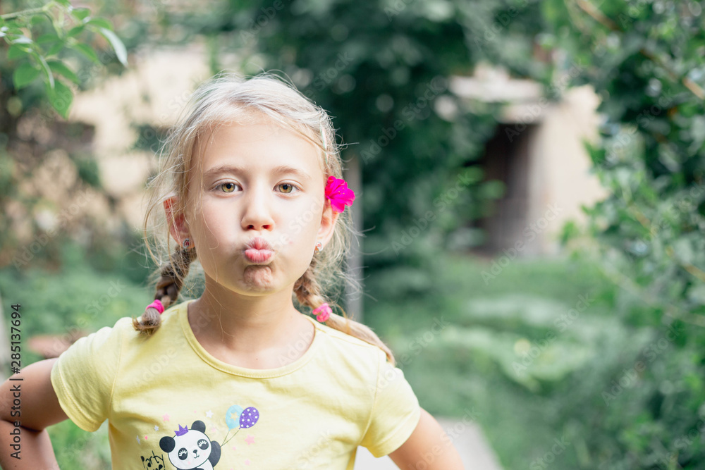 Little girl with yellow eyes in the garden pouting lips funny face expressions Little girl with yellow eyes in the garden pouting lips funny face expressions