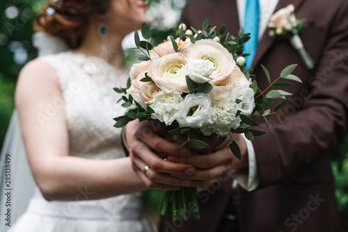 newlyweds are holding hands indoor. wedding bouquet of pink and white roses. wedding day.wedding concept. two gold wedding rings the groom and the bride's hand in hand
