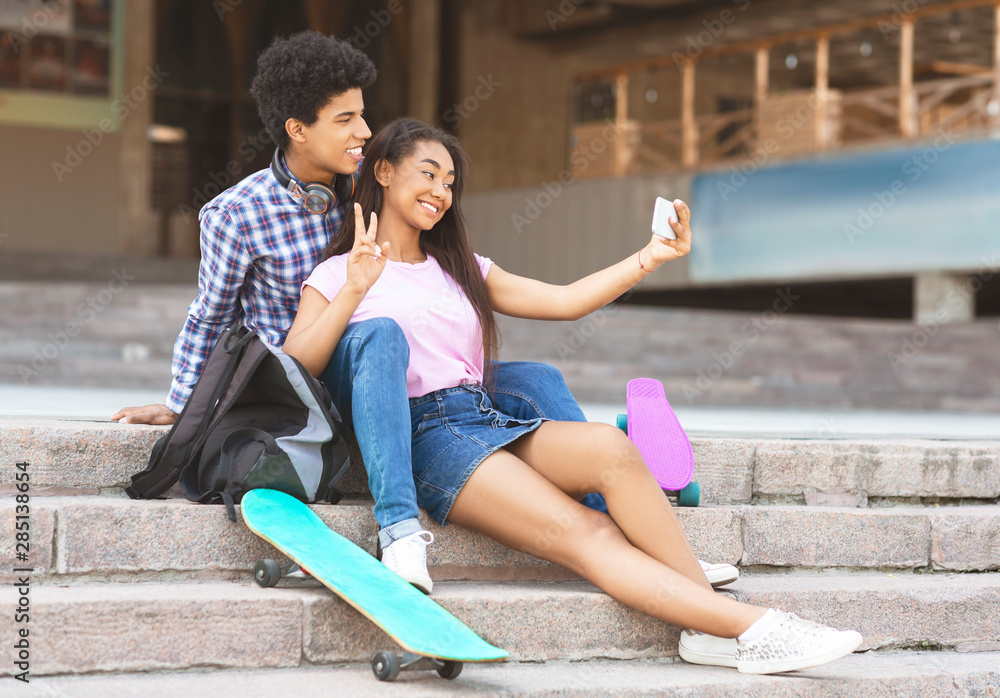 Teenage couple posing for selfie using camera on smartphone