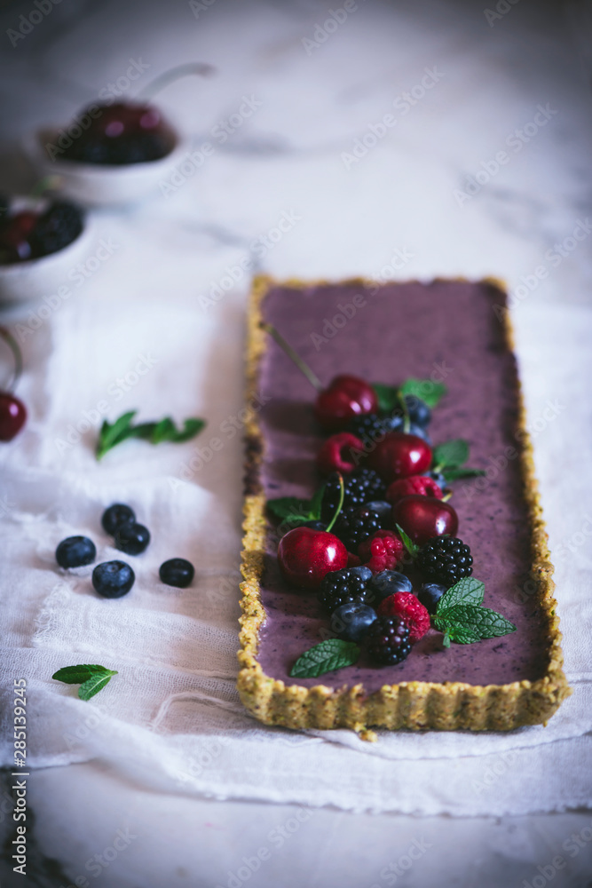 From above ripe tasty cherry blackberry blueberry raspberry with green stems on top of appetizing rectangular cake on white table