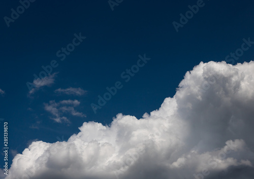 Fluffy white summer clouds isolated on indygo blue sky.
