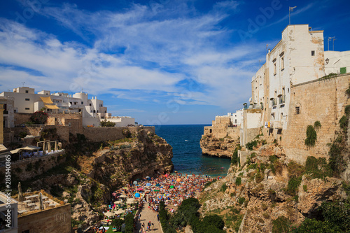 Beautiful view of Polignano a Mare with a lot of tourists sunbathing on the beach, Bari Province, Apulia (Puglia), southern Italy.