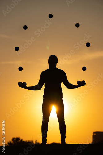 Silhouette of a man Juggling with Balls at Sunset